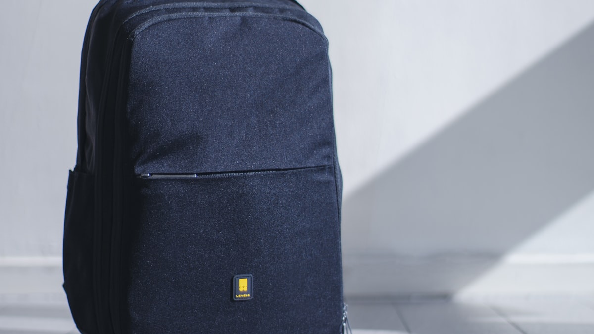 A navy laptop backpack standing against a white wall