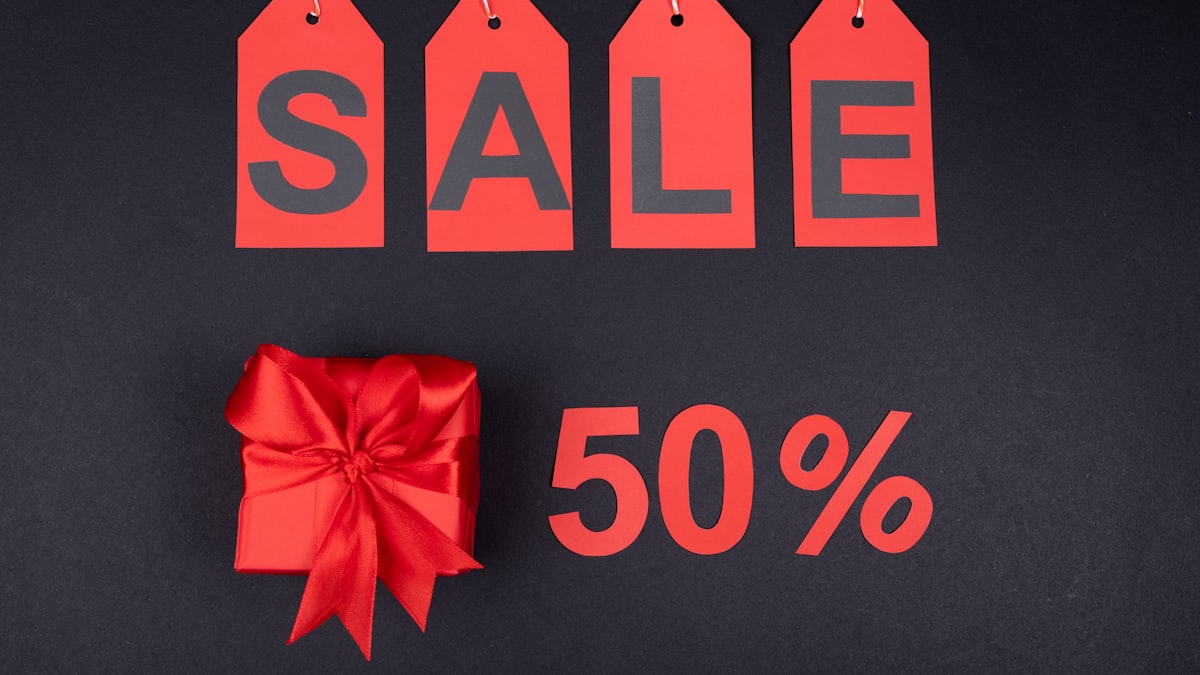 Red SALE price tags and a 50% off sign on a dark background