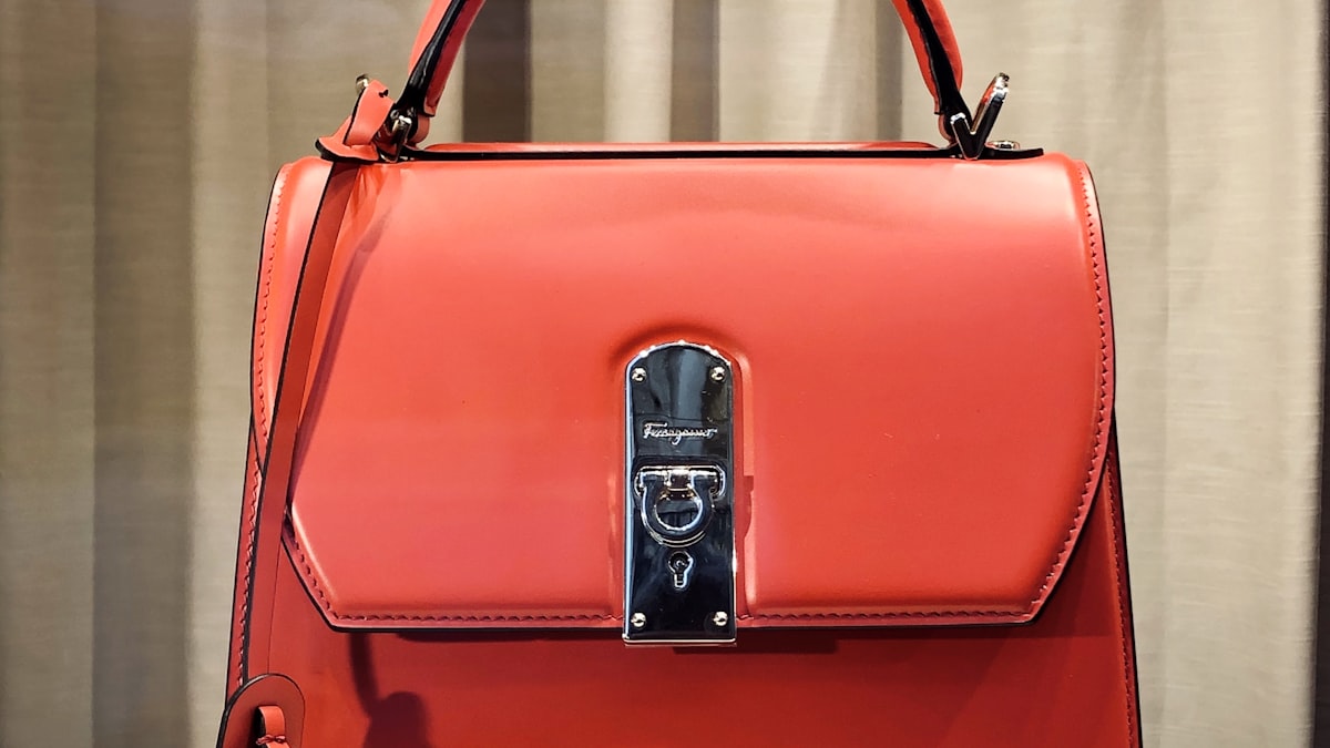 A coral leather designer handbag with a silver clasp
