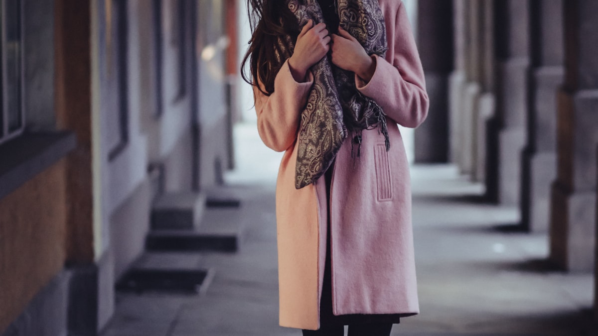Woman in a pink wool coat and paisley scarf on a city street