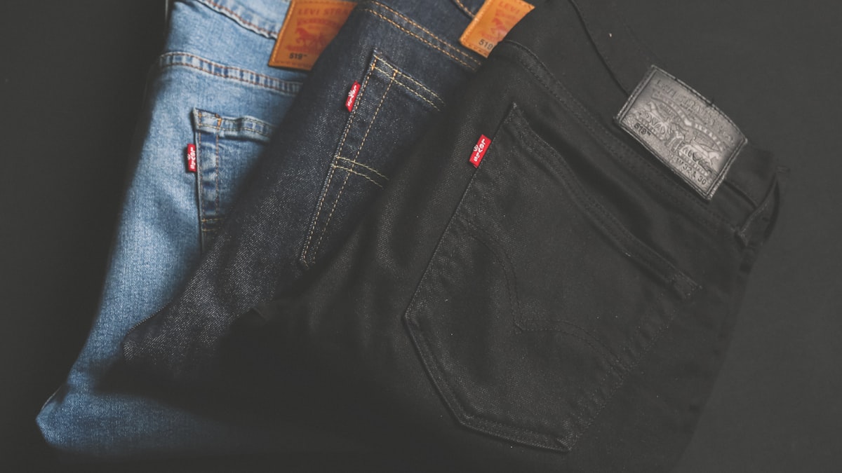 Three folded pairs of jeans in light wash, dark wash and black