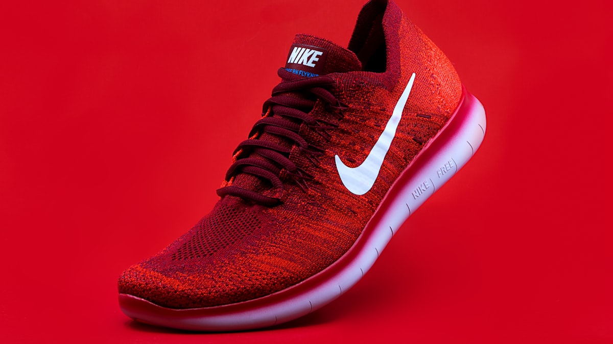 A red knit running shoe photographed on a red background