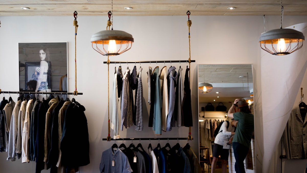 The interior of a clothing boutique with rails and a mirror