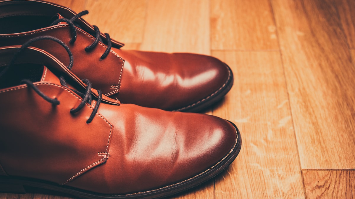 A clean pair of brown leather lace-up shoes on a wooden floor