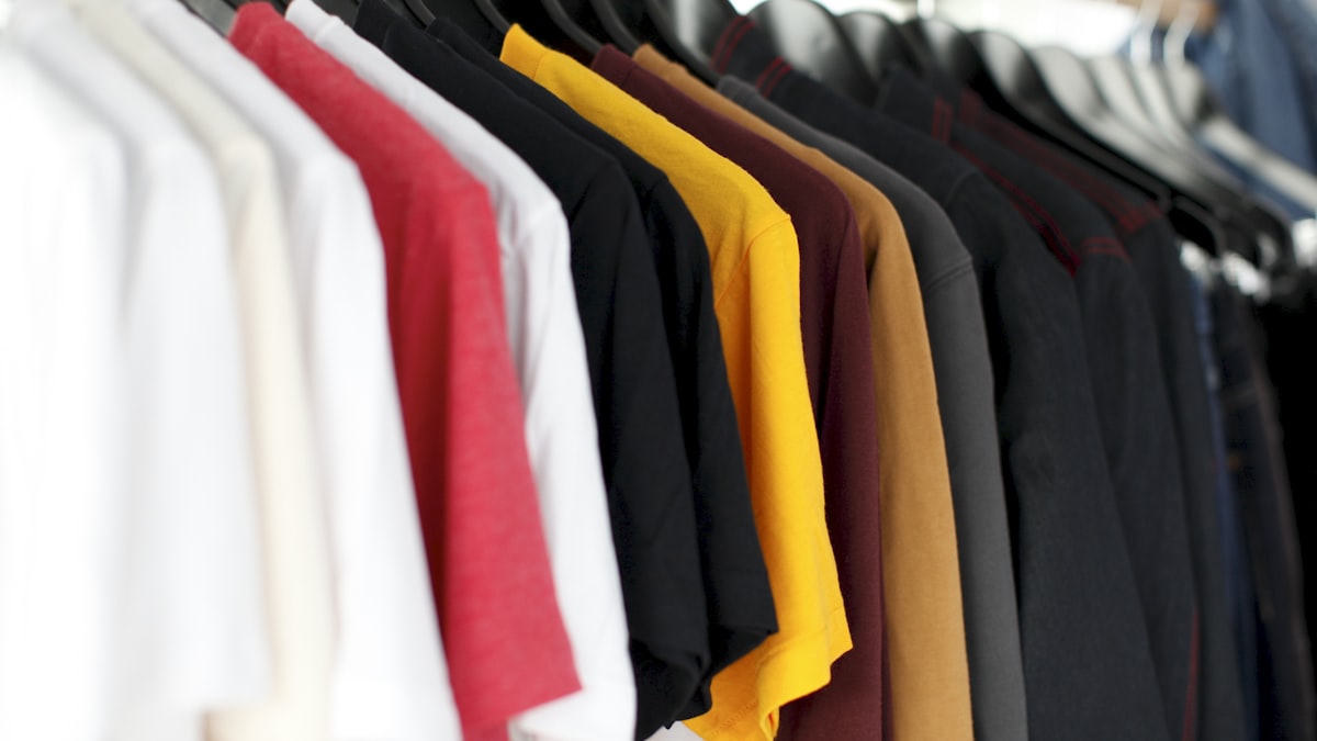A rail of basic t-shirts in white, red, black, yellow and navy