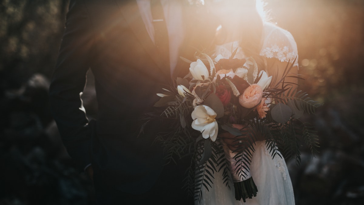 Bride and groom holding a bouquet in warm golden light